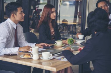 Bir grup iş adamı konferans odasında toplantı yapıyor. İşletme doküman grafiği ofis masasına danışmak için beyin fırtınası yapıyorlar. Çeşitli etnik gruplardan iş adamları beyin fırtınası yapıyor ve birlikte çalışıyorlar..