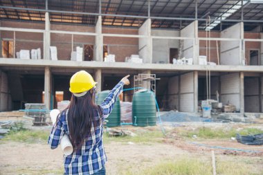 İnşaat mühendisi kadın işçi sanayisinde ekose gömlekli, beyaz kasketli, inşaat işçisi. Mimari mühendis kadın memur emlak projesine bakıyor.