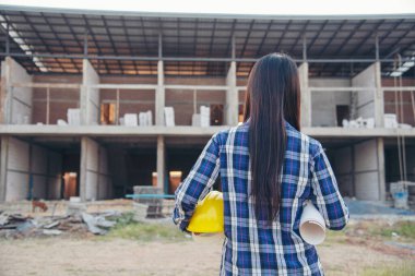 İnşaat mühendisi kadın işçi sanayisinde ekose gömlekli, beyaz kasketli, inşaat işçisi. Mimari mühendis kadın memur emlak projesine bakıyor.