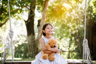 Yeşil Park 'ta oyuncak ayıya sarılırken mutlu çocuk. Oyuncak ayı, küçük çocuklar için en iyi arkadaş tatlı kız. Otizm mutlu bir şekilde oyun bahçesinde birlikte oynayarak mutlu bir aile sevgisi ve sıcacık kucaklaşmayı hisseder.
