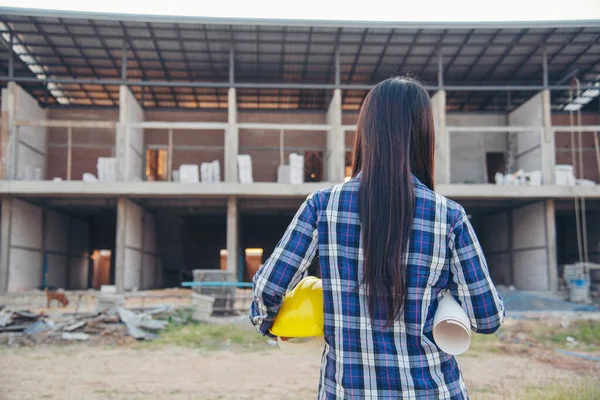 İnşaat mühendisi kadın işçi sanayisinde ekose gömlekli, beyaz kasketli, inşaat işçisi. Mimari mühendis kadın memur emlak projesine bakıyor.