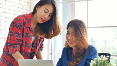 Ofis masasında kendine güvenen iki kadının birlikte çalışması mutluluktur. Bilgisayar şirketi ile çalışan takım ortakları. Asyalı iş arkadaşı arkadaşlığı gülen yüzle iş başında.