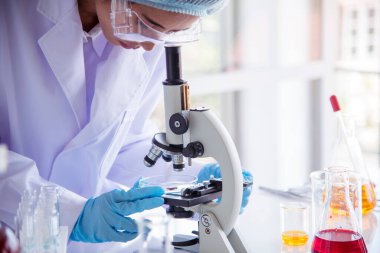 Laboratuvardaki kadın bilim adamı mikroskop tıbbi testine ve biyoloji kimyasına bakıyor. Bilimsel eczane genetik araştırmalarını analiz eden kadın teknisyen laboratuarı. Kimya Tıp Laboratuvarı