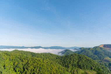 Güzel dağ manzarası sisli rüzgarlı dağ sıraları yeşil Asya arazisi. Yeşil çayır arazisi. Gün doğumunda mavi bulutlu gökyüzü. Kırsal kesimde güneş ışığı cenneti manzarası