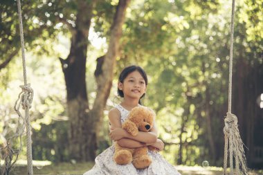 Yeşil Park 'ta oyuncak ayıya sarılırken mutlu çocuk. Oyuncak ayı, küçük çocuklar için en iyi arkadaş tatlı kız. Otizm mutlu bir şekilde oyun bahçesinde birlikte oynayarak mutlu bir aile sevgisi ve sıcacık kucaklaşmayı hisseder.