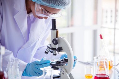 Kapalı alan kadın bilim adamı laboratuvarda düşürücü kullanıyor. Bilimsel mikroskop tıbbi testi, biyoloji kimyası araştırması. Kadın teknisyen laboratuarı kan bilimsel ilaç araştırmalarını inceliyor..