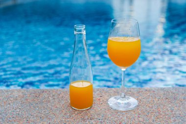 Portakal suyu, turistik yerlerdeki mavi yüzme havuzunda taze tatlı içecek. Portakallı, sulu, sağlıklı, moktail organik, soğuk meyve suyu bardağı. Sağlıklı tatlı içecek soğuk içecekler