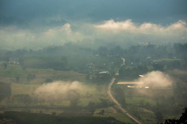 Güzel dağ manzarası sisli rüzgarlı dağ sıraları yeşil Asya arazisi. Yeşil çayır arazisi. Gün doğumunda mavi bulutlu gökyüzü. Kırsal kesimde güneş ışığı cenneti manzarası