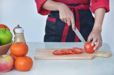 Kadın aşçı elini kapat. Kırmızı domates doğra. Meyve sebzesi hazırla. Kırpılmış Kadın elleri bıçakla organik domates doğruyor. Kadın şefler ellerinde pirzola, tahta kesme tahtası ev mutfağı.