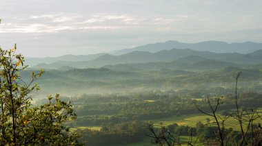 Dağ manzarasında dramatik bir gün batımı. Güzel manzara sisli tepeler alacakaranlık vakti. Mavi altın gökyüzü gün doğumu dramatik manzara dağları. Şafak vakti altın rengi alacakaranlık zamanı güneş ışığıyla bulutlu manzara