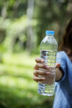 Dikey Genç Kadın Su İçen Şişe Açık Park Gezgini. Asyalı kadın içme suyu şişesi sağlıklı ve mutlu bir insan. Dikey görüntüler. Mineral içeceği şişesi tutan güzel Asyalı kadınlar.