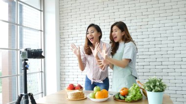 Asyalı vlogger canlı yayında sağlıklı beslenme tarzı hakkında yorum yapıyor. İki genç bayan arkadaş blogcu mutlu bir yaşam tarzı sunuyor. Sebze, meyve, vejetaryen ürünleri nasıl yenir. İki kadın sosyal medya vlog 'undan bahsediyor