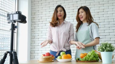 Asyalı vlogger canlı yayında sağlıklı beslenme tarzı hakkında yorum yapıyor. İki genç bayan arkadaş blogcu mutlu bir yaşam tarzı sunuyor. Sebze, meyve, vejetaryen ürünleri nasıl yenir. İki kadın sosyal medya vlog 'undan bahsediyor