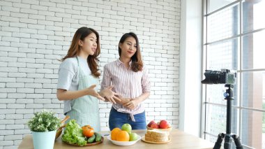 İki Asyalı vlogcu birlikte sağlıklı bir yaşam tarzı gözden geçiriyorlar. İki Genç Kadın Arkadaş blogcusu Mutlu Yaşam Biçimi Canlı Yayın. İki kadın sosyal medyadan konuşuyor, merhaba de.