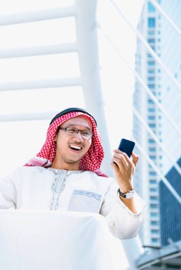 Portreli İslami İslamcı adam akıllı telefon uygulama takvimi kullanıyor. Güncel müslüman el ele tutuşmaya odaklanıyor. Dikey ufuk çizgisi olan Arap erkekleri başörtüsü takıyor.