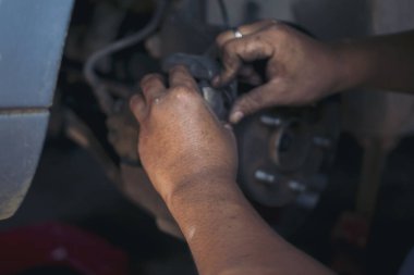 Tamirci ellerini kapayıp araba tamirhanesini tamir ediyor. Lastik değiştiriyor. Adam elleri şok emici makine araç mekanik servisini tamir ediyor. Araç bakım mühendisi.