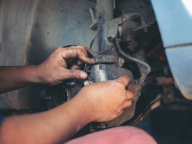 Tamirci ellerini kapayıp araba tamirhanesini tamir ediyor. Lastik değiştiriyor. Adam elleri şok emici makine araç mekanik servisini tamir ediyor. Araç bakım mühendisi.