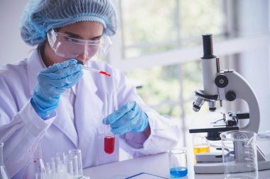 Kimyasal test tüpü tutan bilim laboratuarındaki bilim kadını. Cam tüp tanısı için kırmızı damlayı tutan laboratuvar teknisyeni kan örneği. Tıbbi kimya testinde çalışan Asyalı kadın bilim adamı