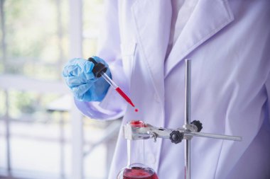 Kimyasal test tüpü taşıyan kadın bilim laboratuvarını kapatın. Kırpılmış laboratuvar teknisyeni cam tüpten kan örneği alıyor. Tıbbi kimyayı test eden bilim kadını.