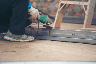 İnşaat işçisi elleri kaynak makineleri ile metal kıvılcımlar saçıyor. Erkek elleri koruyucu eldiven giyer. Alev metali, ateş demiri atölyesini keser. Çilingir kaynak makinesi kullanarak metal işlemini kesti