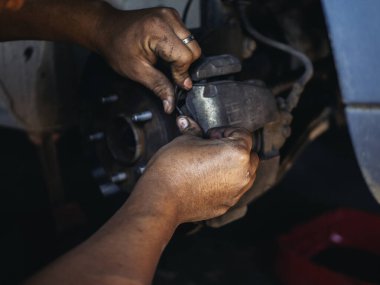 Tamirci ellerini kapayıp araba tamirhanesini tamir ediyor. Lastik değiştiriyor. Adam elleri şok emici makine araç mekanik servisini tamir ediyor. Araç bakım mühendisi.