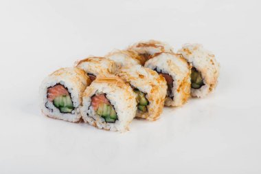 Somon, salatalık ve krem peynirli suşi ruloları beyaz arka planda izole edilmiş ton balığı talaşlarıyla kaplı.. 