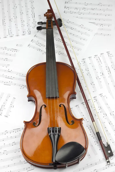 Скрипка и лук на нотах — стоковое фото