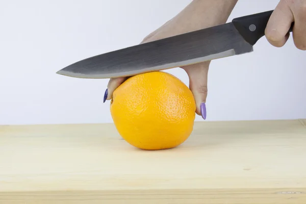 Corte a mano una naranja en una tabla de madera — Foto de Stock