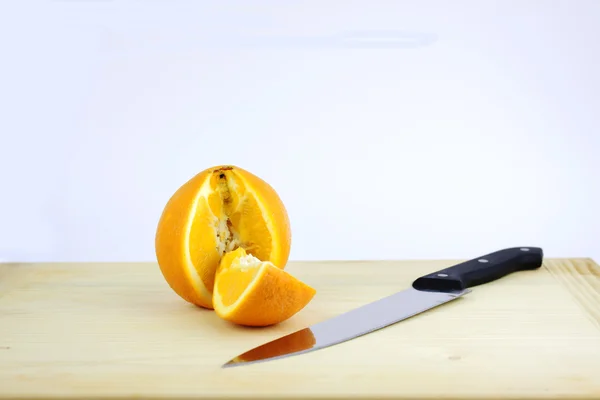 Corte naranja en una tabla de madera cerca de un cuchillo — Foto de Stock