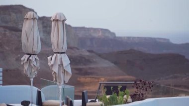 Yunanistan 'ın Santorini kentindeki bir restoran terasında rüzgarlı bir sonbahar gününde güneş şemsiyeleri toplandı.
