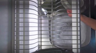 Kurutma dolabının içinden kaydedilen paslanmaz çelik bir lavaboda yıkanan tabakların yukarıdan aşağı bakışı..