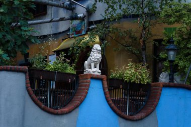 Viyana, Avusturya - 5 Ekim 2025 - Aslan heykeli Hundertwasser Köyü 'ndeki Terrassencafe im Hundertwasserhaus' da mavi bir duvara monte edildi.