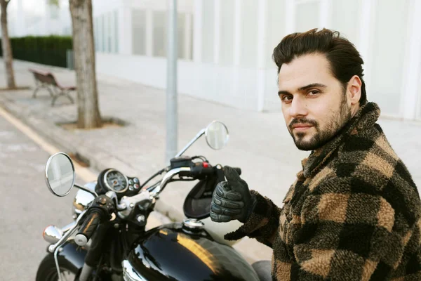 Porträtt av ung skäggig cyklist man på motorcykel utomhus på stadens gator. — Stockfoto