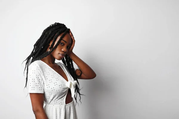 Young black woman with sad, pensive, reflective look, against white wall background with copy space for your text .