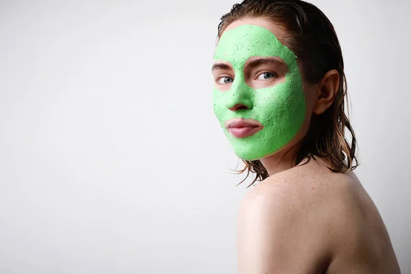 Retrato de mujer feliz con mascarilla facial verde aguacate hidratante aislada sobre fondo rosa. Belleza y cuidado de la piel. —  Fotos de Stock