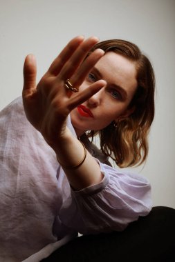 Beyaz duvarın üzerinde elini tutan genç bir kadının dikey yakın çekimi.. 