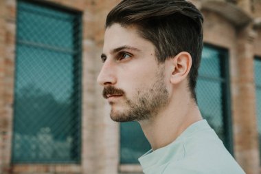 Açık havada poz veren beyaz bir gencin yan resmi..