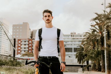 Bisikletiyle dışarıda poz veren genç adam. Yaşam tarzı.