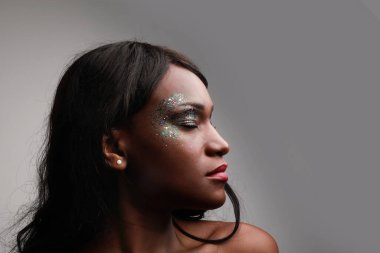 Beyaz duvarın üzerinde poz veren Afrikalı genç bir kadının yakın çekimi. Güzellik konsepti.