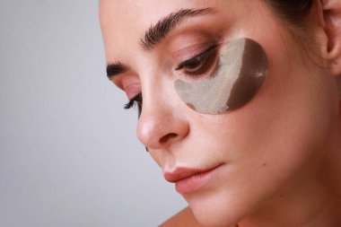 Hidrojel göz bandı olan beyaz tenli güzel beyaz bir kadının yakın çekimi..