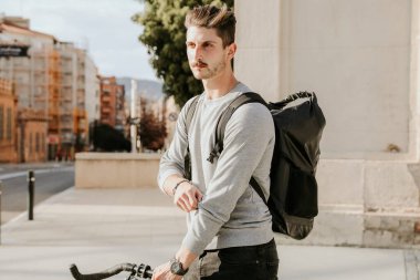 Gündelik giysiler içinde beyaz bir adam akşam vakti yolda bisiklet sürüyor.