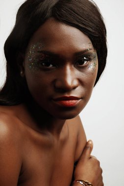 Beyaz duvarın üzerinde poz veren güzel Afrikalı genç bir kadın. Dikey yakın plan.