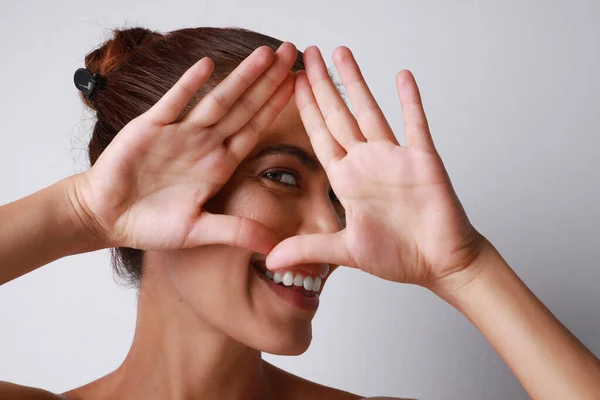 Gülümseyen ve neşeli olgun bir kadın, beyaz duvarın üzerinde poz veriyor. izole.