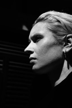Siyah beyaz yakın plan genç kadın portresi, dışarıda uzun saçlı poz veriyor.