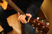 Cropped photo of man practicing in playing acoustic guitar.