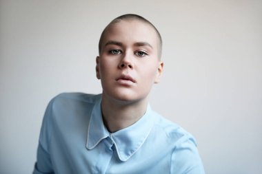 Portrait of a beautiful bald woman wearing blue clothes.