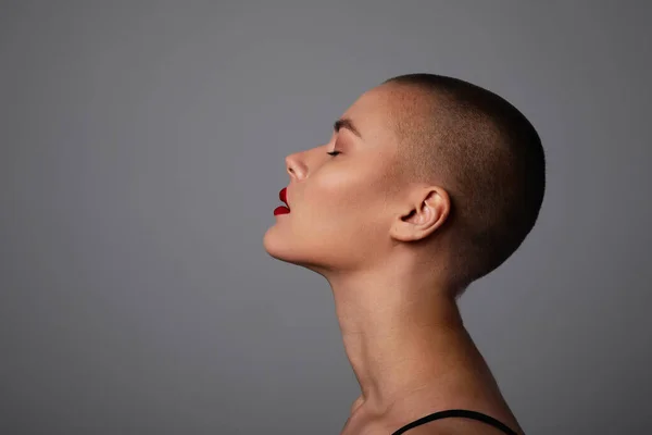 Side portrait of a beautiful bald woman. Studio shot.
