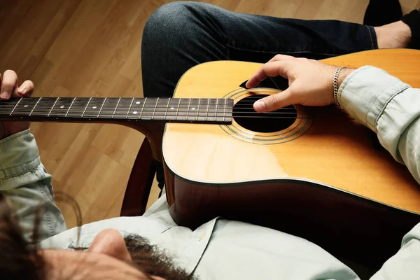 Beskuren bild av människan som övar på att spela akustisk gitarr. Ovanifrån. — Stockfoto
