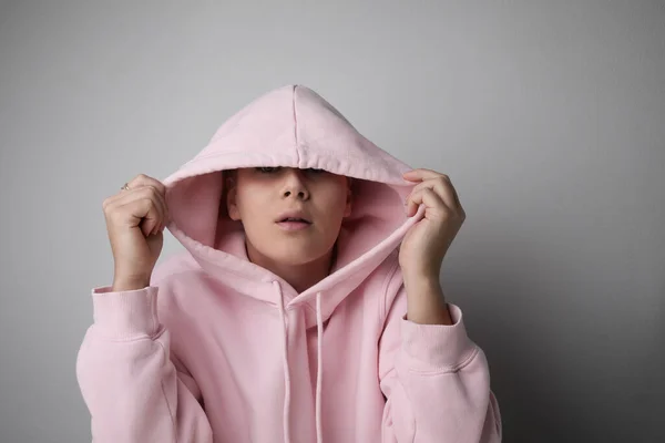 Nahaufnahme einer jungen Frau mit Glatze in rosa Kapuzenpulli, die im Studio posiert. — Stockfoto