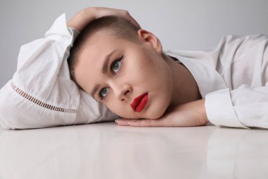 Stüdyoda poz veren sivilceli kel bir kadının yakın çekimi..